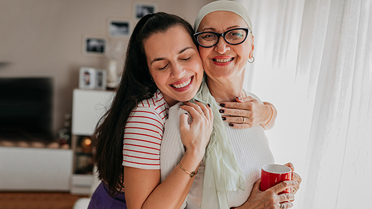 person with long hair hugging person with head scarf and glasses